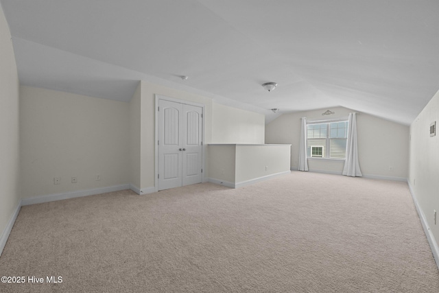 bonus room with light colored carpet and vaulted ceiling