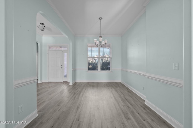 unfurnished dining area featuring wood-type flooring, ornamental molding, and a chandelier