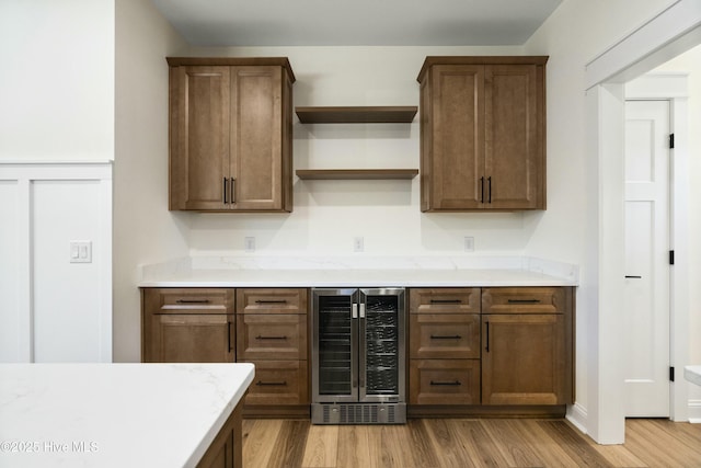 bar featuring light hardwood / wood-style floors and beverage cooler