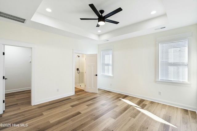 unfurnished bedroom with hardwood / wood-style floors, a tray ceiling, and ceiling fan