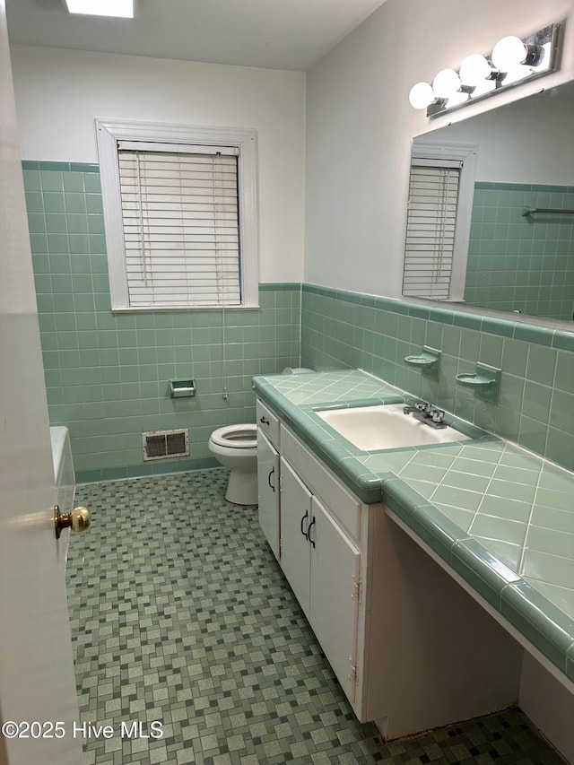 bathroom featuring tile patterned floors, vanity, tile walls, and toilet