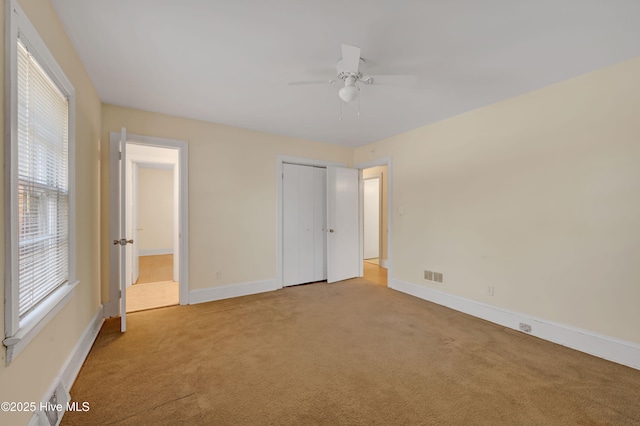 unfurnished bedroom with light carpet, a closet, and ceiling fan