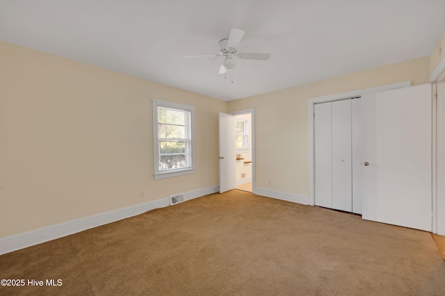 unfurnished bedroom with ceiling fan, light colored carpet, and a closet