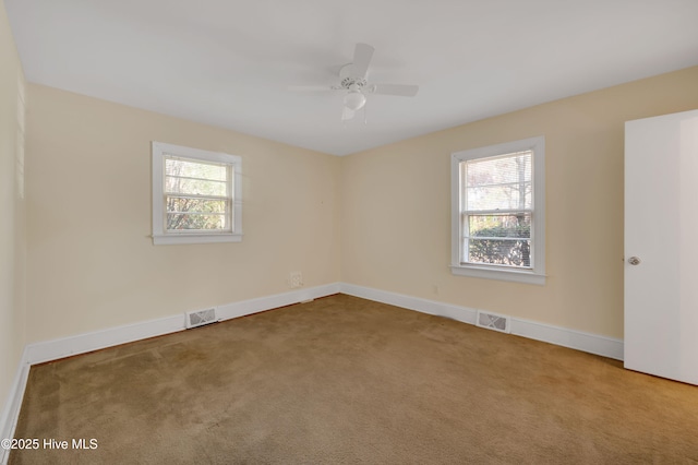 carpeted empty room with a wealth of natural light and ceiling fan