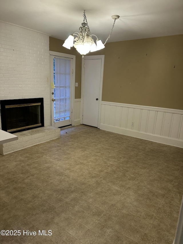 unfurnished living room with a notable chandelier and a fireplace