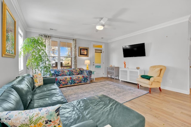 living room featuring visible vents, ornamental molding, a ceiling fan, wood finished floors, and baseboards