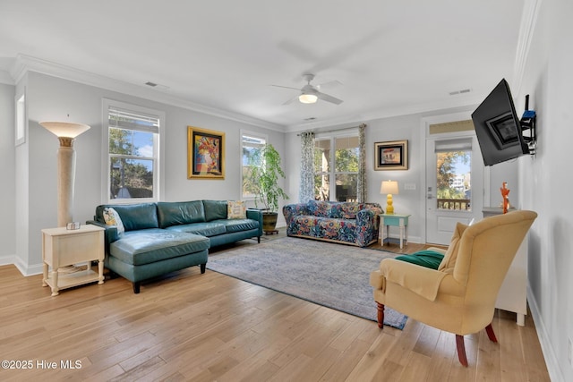 living area featuring visible vents, light wood-style flooring, and ornamental molding