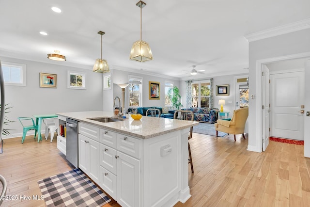 kitchen with decorative light fixtures, ornamental molding, light wood-style floors, white cabinets, and a sink