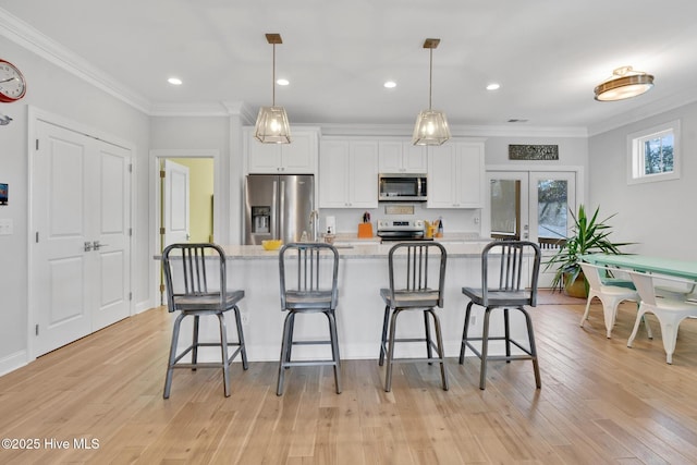 kitchen with white cabinets, ornamental molding, french doors, and stainless steel appliances