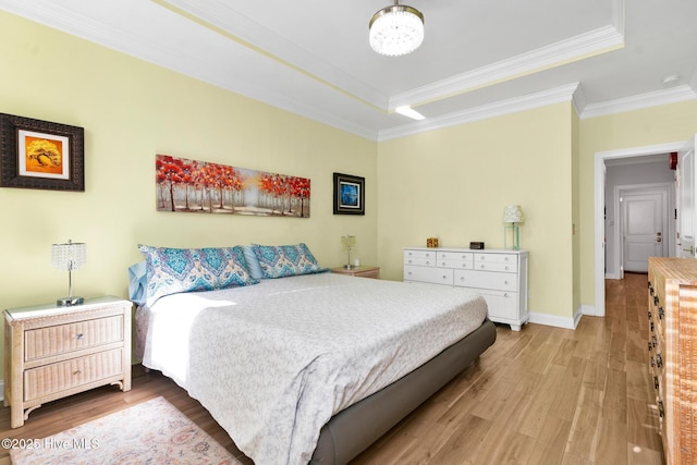 bedroom featuring crown molding, wood-type flooring, a chandelier, a raised ceiling, and connected bathroom