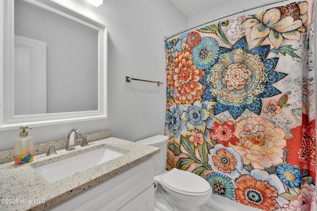 bathroom featuring toilet, a shower with shower curtain, and vanity