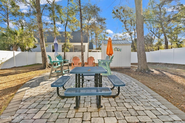 view of patio / terrace with a shed, a fenced backyard, outdoor dining area, and an outdoor structure