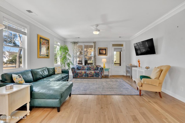 living room featuring a healthy amount of sunlight, crown molding, and light wood-style floors