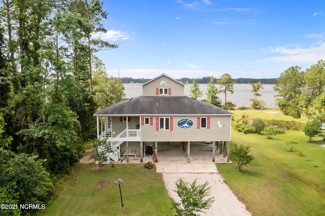 view of front facade featuring covered porch, a carport, a water view, and a front lawn