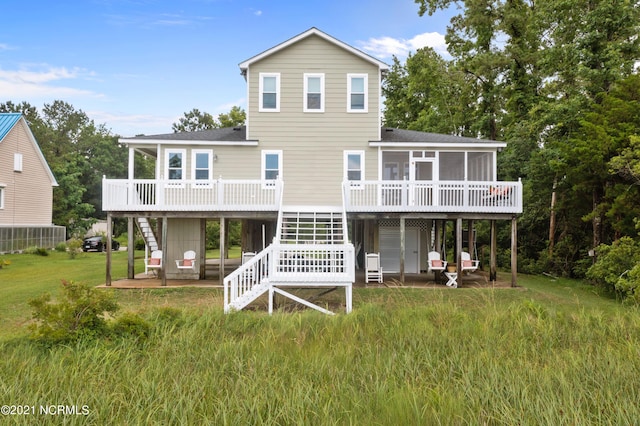 back of property with a sunroom, a patio area, a deck, and a lawn