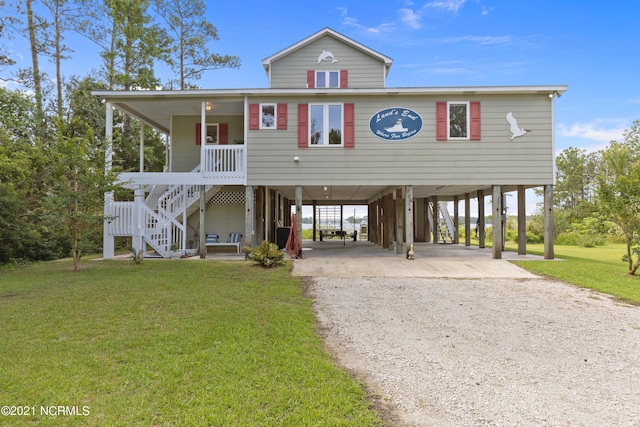 coastal inspired home with a front yard, a carport, and covered porch