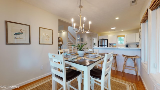 dining room with light wood-type flooring and a notable chandelier