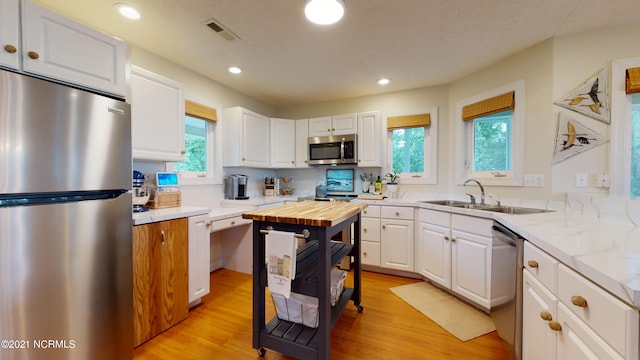 kitchen with white cabinetry, sink, light hardwood / wood-style floors, and appliances with stainless steel finishes