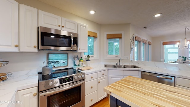 kitchen with light stone countertops, sink, white cabinets, and stainless steel appliances