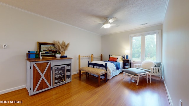 bedroom featuring ceiling fan, crown molding, wood-type flooring, and a textured ceiling