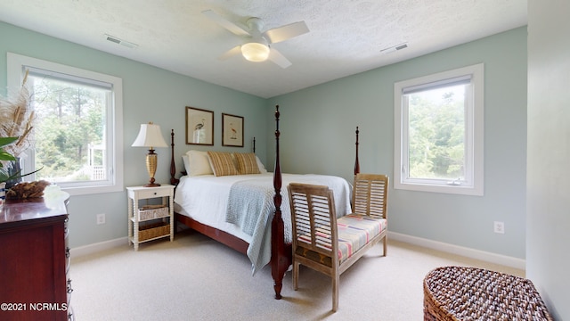 carpeted bedroom with multiple windows, a textured ceiling, and ceiling fan