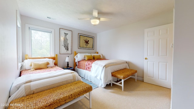 carpeted bedroom featuring ceiling fan and a textured ceiling