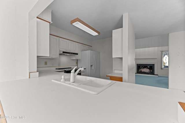 kitchen featuring stainless steel range with electric cooktop, white cabinetry, kitchen peninsula, white fridge with ice dispenser, and sink