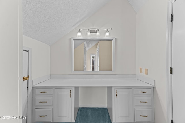 bathroom with a textured ceiling, vanity, and lofted ceiling