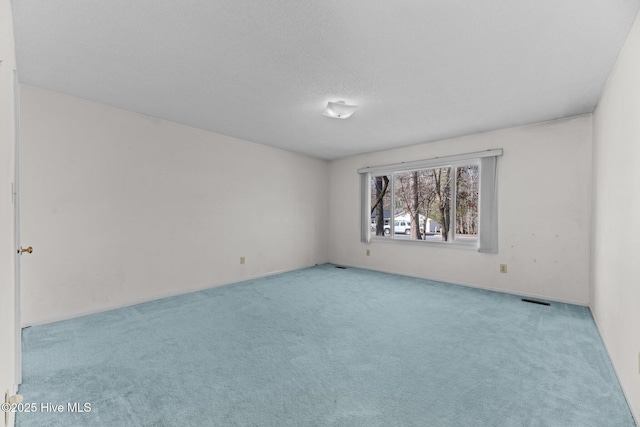 spare room featuring light carpet and a textured ceiling