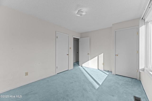 unfurnished bedroom featuring light colored carpet and a textured ceiling