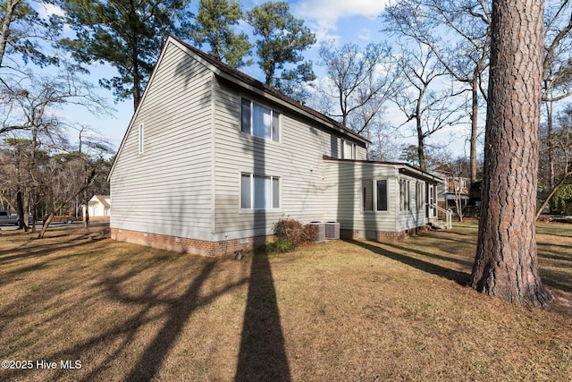 view of side of property featuring a lawn and central AC