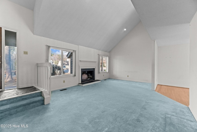 unfurnished living room with vaulted ceiling and carpet flooring