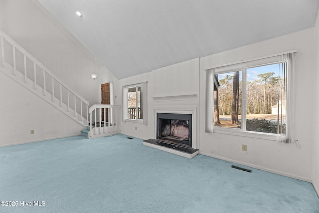 unfurnished living room featuring high vaulted ceiling and carpet flooring