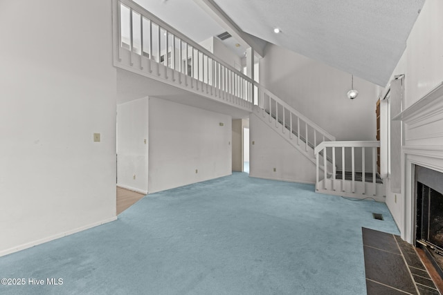 unfurnished living room featuring high vaulted ceiling, a textured ceiling, and carpet floors