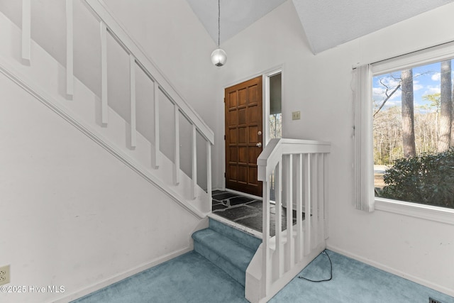 stairway with vaulted ceiling, plenty of natural light, and carpet flooring