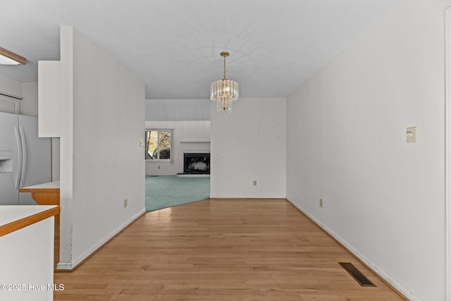 unfurnished dining area with light wood-type flooring and a chandelier