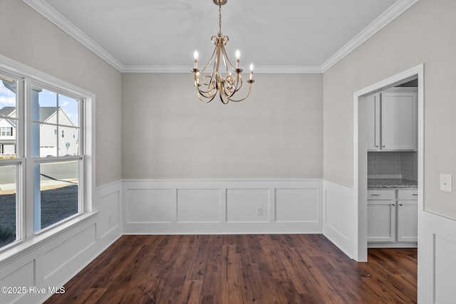 unfurnished dining area featuring ornamental molding, a notable chandelier, and dark hardwood / wood-style flooring