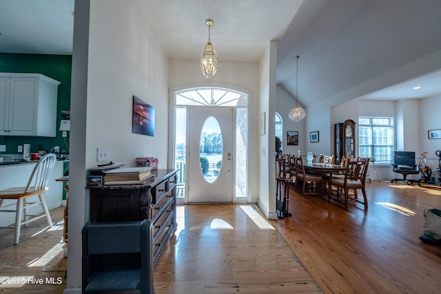 entryway featuring light hardwood / wood-style floors, a towering ceiling, and a notable chandelier