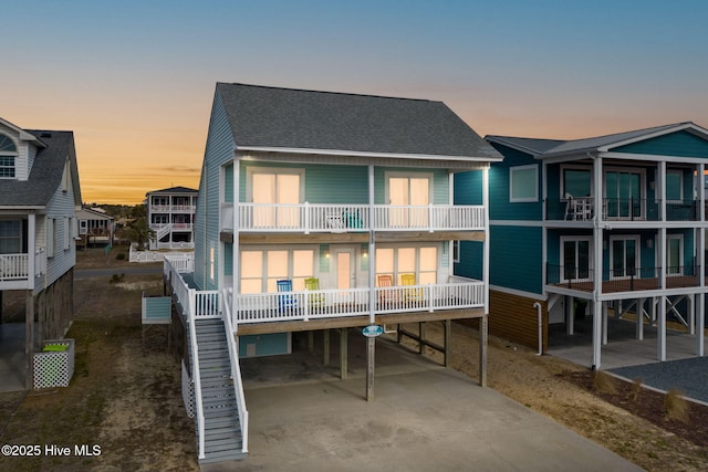 back house at dusk featuring a carport and a balcony