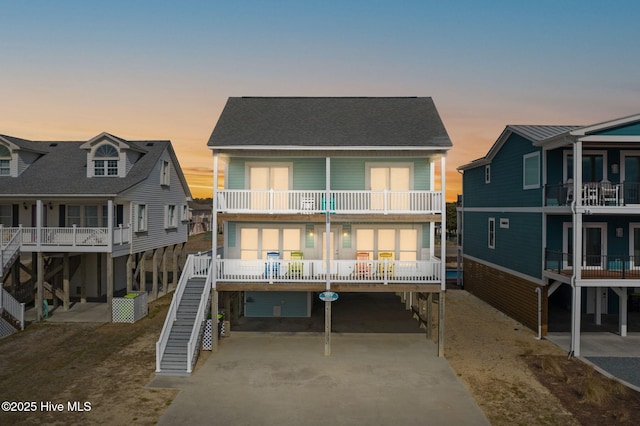 back house at dusk with a carport and a balcony