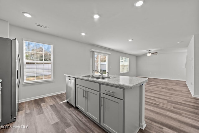 kitchen featuring appliances with stainless steel finishes, ceiling fan, sink, gray cabinets, and an island with sink