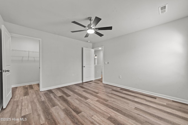 unfurnished bedroom with a closet, light hardwood / wood-style floors, a spacious closet, and ceiling fan