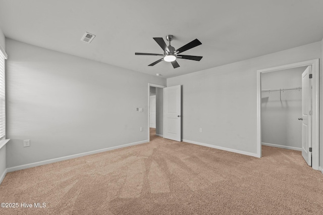 unfurnished bedroom featuring ceiling fan, a closet, light carpet, and a spacious closet