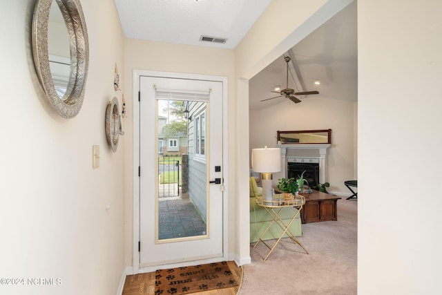 entryway featuring lofted ceiling, light colored carpet, ceiling fan, a premium fireplace, and a textured ceiling