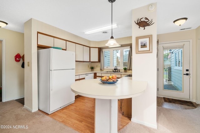 kitchen featuring sink, white appliances, hanging light fixtures, and a healthy amount of sunlight