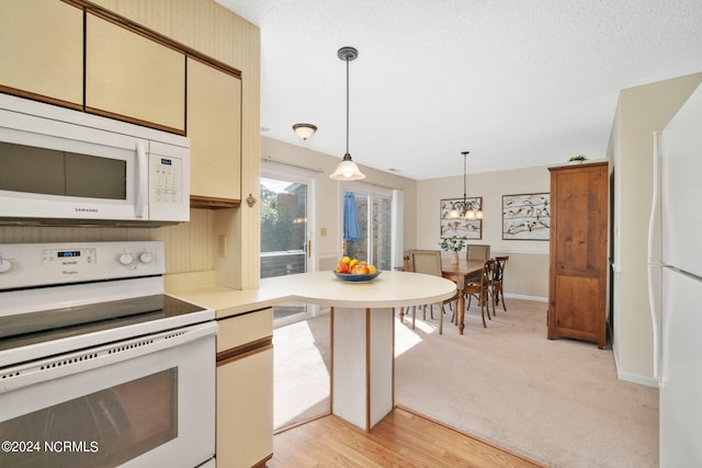 kitchen with pendant lighting, white appliances, light hardwood / wood-style floors, a textured ceiling, and an inviting chandelier