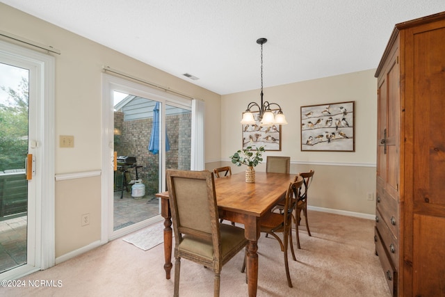 dining area featuring a textured ceiling, light colored carpet, and a chandelier