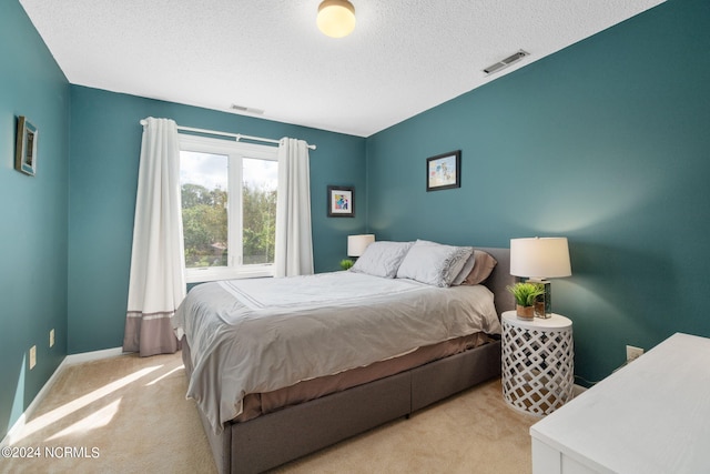 bedroom with light carpet and a textured ceiling