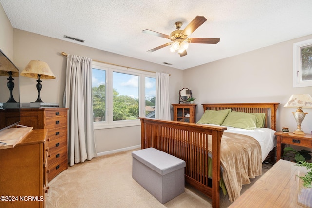 carpeted bedroom with ceiling fan and a textured ceiling