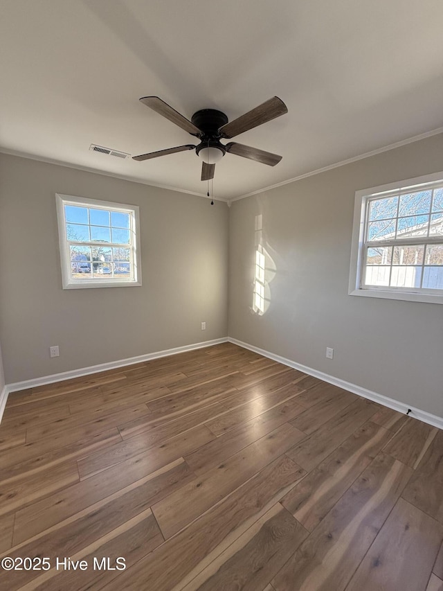 empty room featuring ceiling fan, dark hardwood / wood-style flooring, ornamental molding, and a wealth of natural light